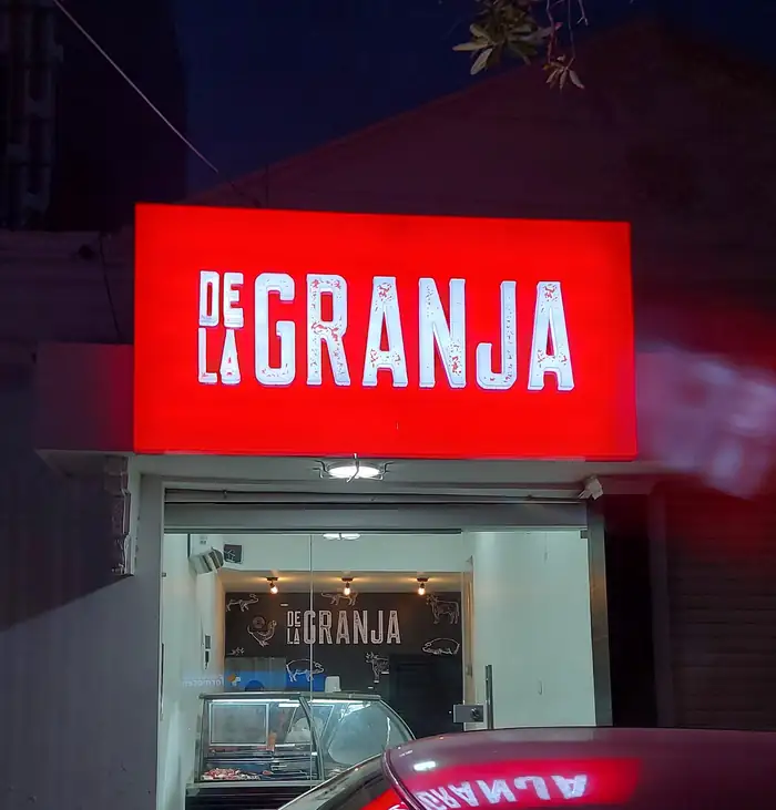 Caja de luz retroiluminada del restaurante De la Granja encendida sobre la entrada del local