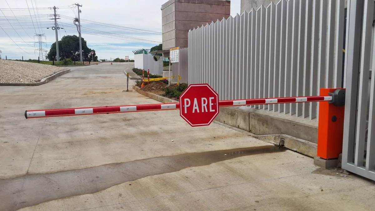 Talanquera con señal PARE y topellanta instaladas en portería industrial